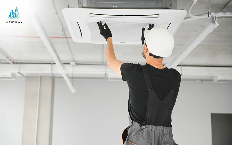 A technician inspects a ceiling-mounted air conditioning unit
