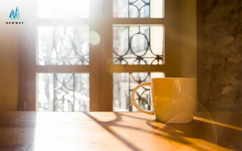 Coffee mug on wooden table in morning light.